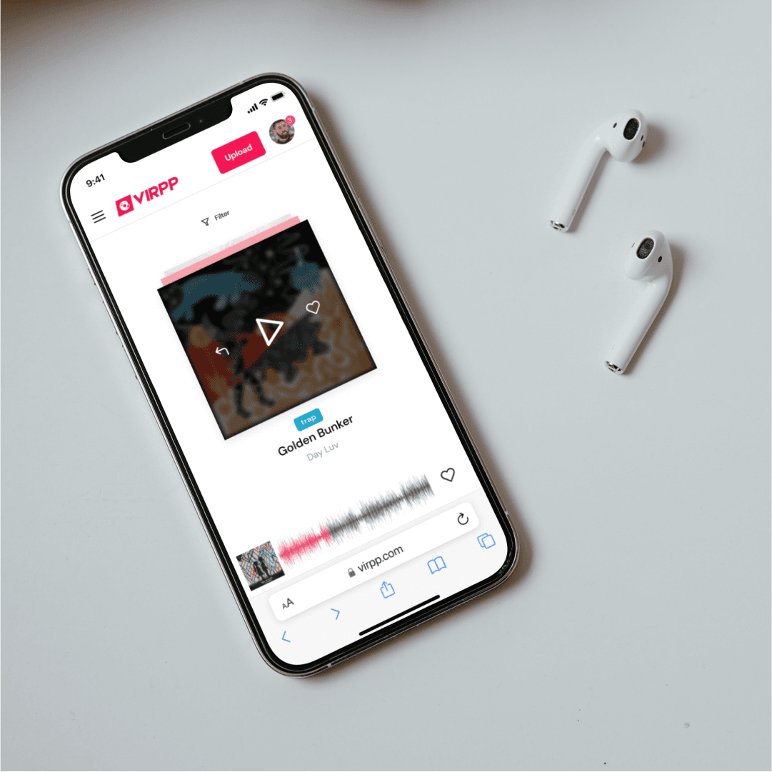 Een telefoon op een tafel naast oordopjes toont de trackpagina met hoesbeeld, afspeelknop en waveform.