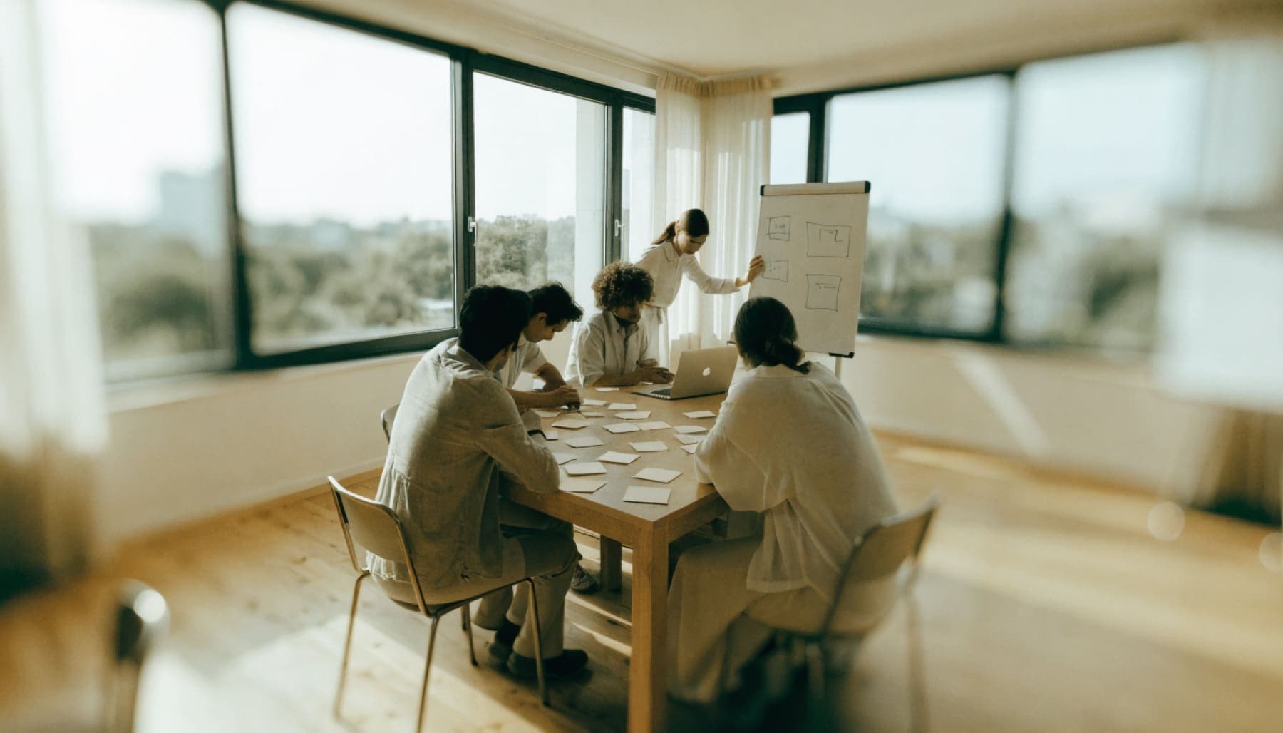 Een managementteam werkt samen aan een tafel vol memobriefjes tijdens een AI-workshop