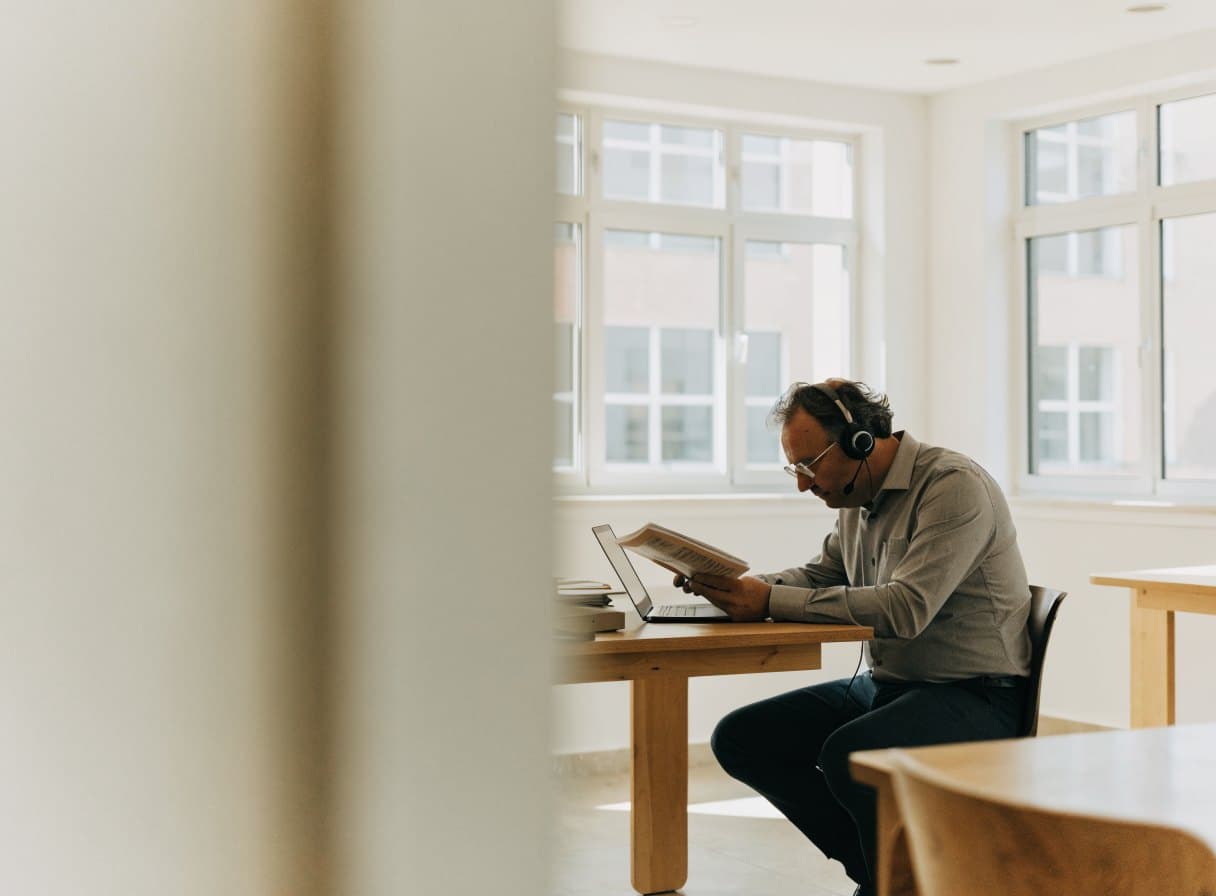 Medewerker met headset leest een document aan een bureau met een laptop