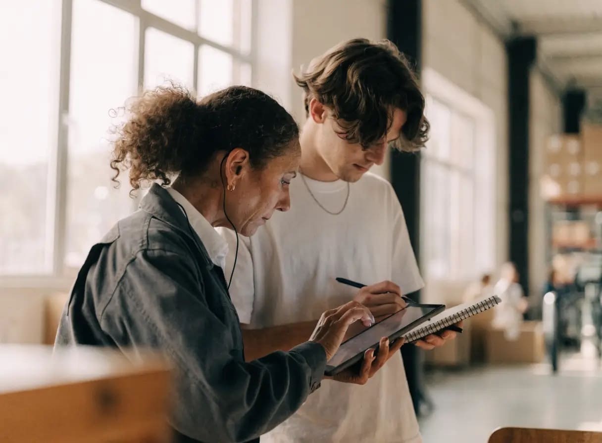 Medewerker test een nieuwe interne applicatie op een tablet terwijl een ontwikkelaar aantekeningen maakt